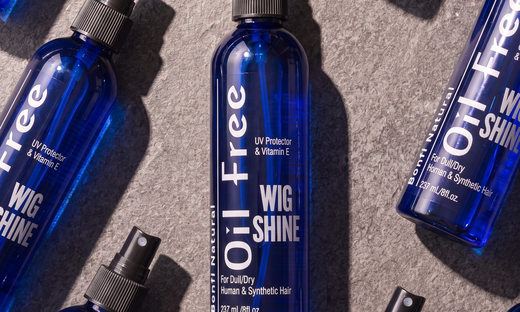 Bonfi Natural Oil-Free Wig Shine bottles laid flat on stone