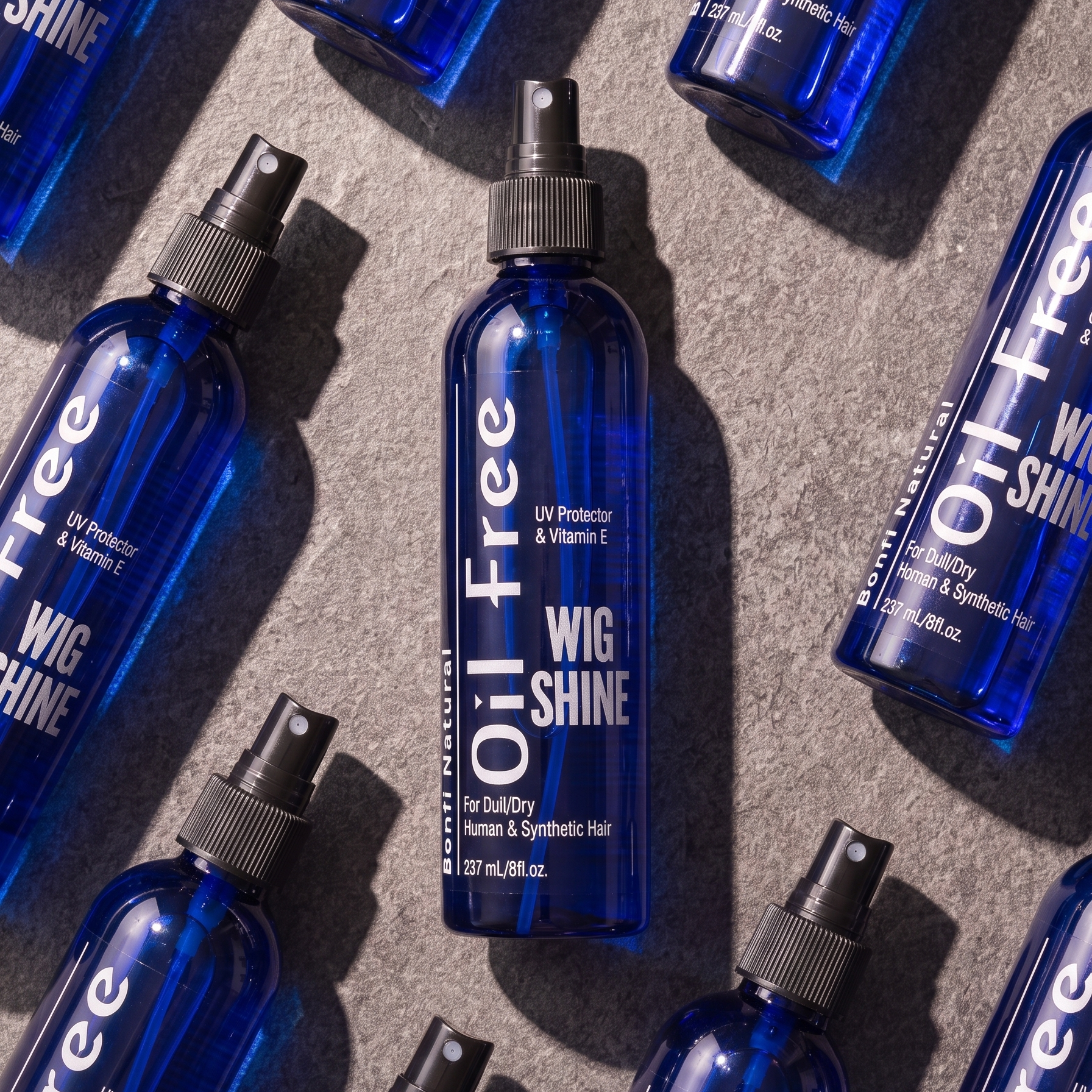 Bonfi Natural Oil-Free Wig Shine bottles laid flat on stone