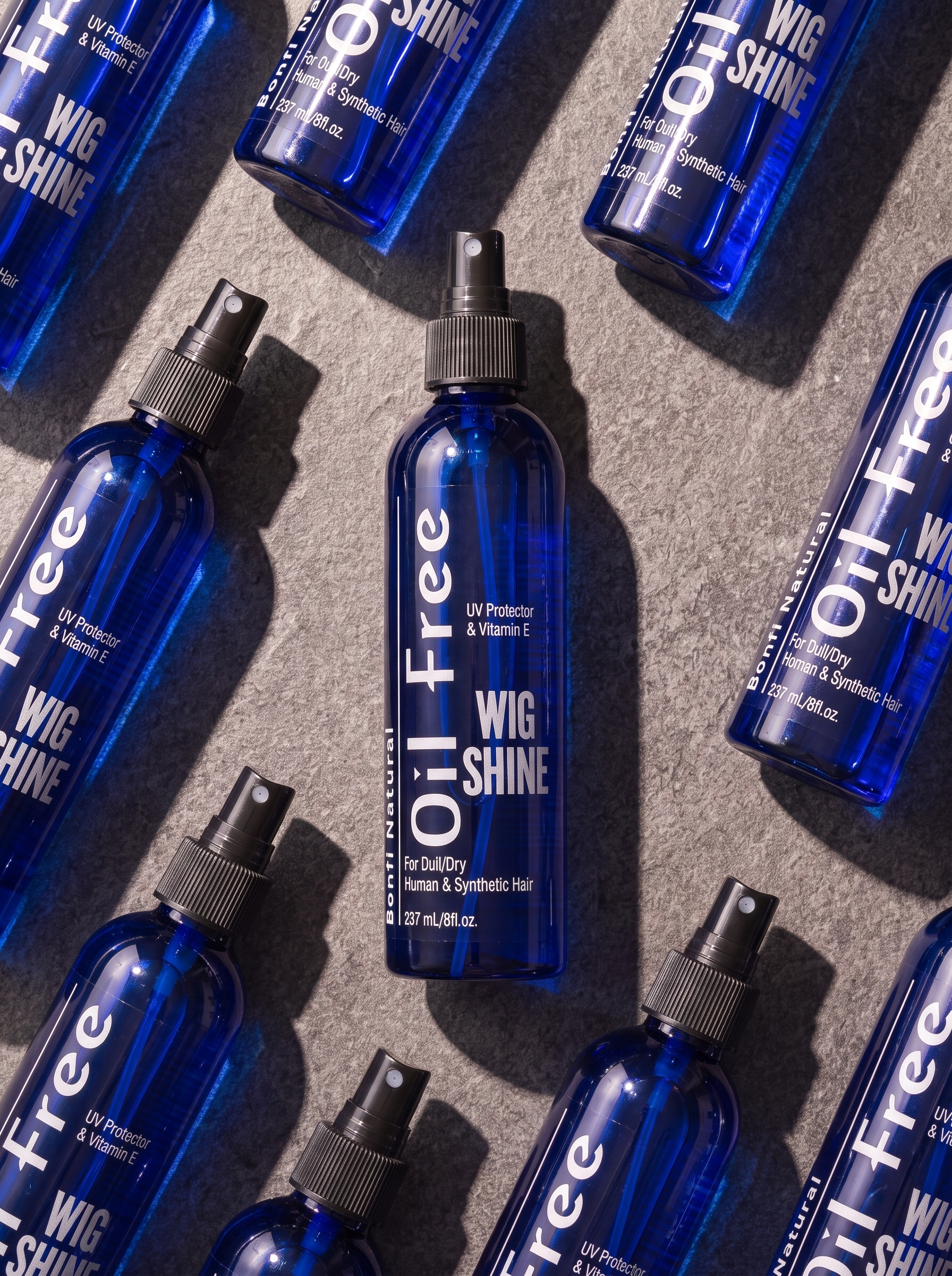 Bonfi Natural Oil-Free Wig Shine bottles laid flat on stone